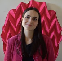 a woman in a pink jacket standing in front of a pink wall